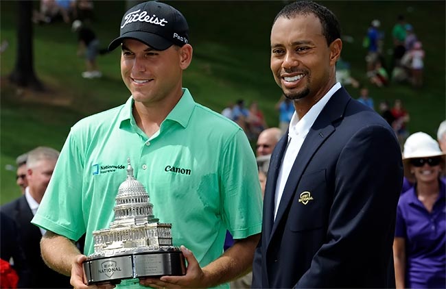 Haas recebe o troféu das mãos de Tiger Woods, o anfitirão do torneio de golfe ao lado de Washington