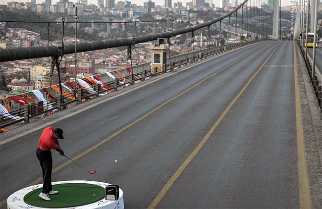 Tiger bate driver para fazer bola de golfe cruzar da Europa para a Ásia, sobre a Ponte do Bósforo