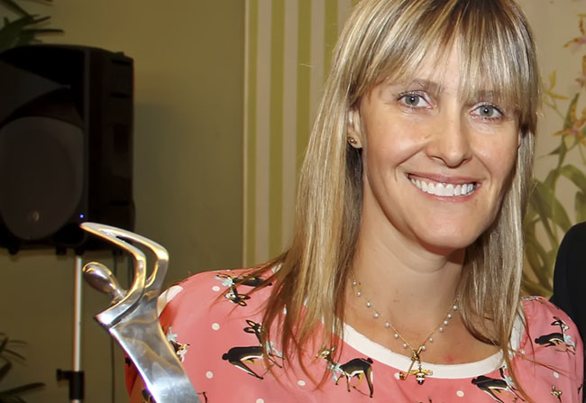 Melinda com troféu ganho na França: profissional e professora de golfe com carteira e diploma